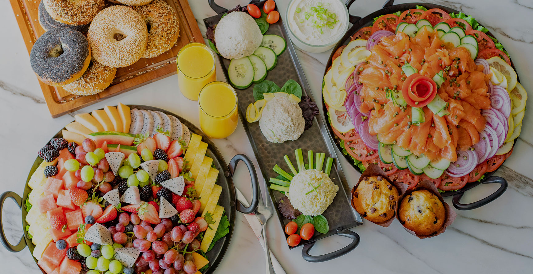 catering dishes including fresh fruit platter, bagels, orange juice and more