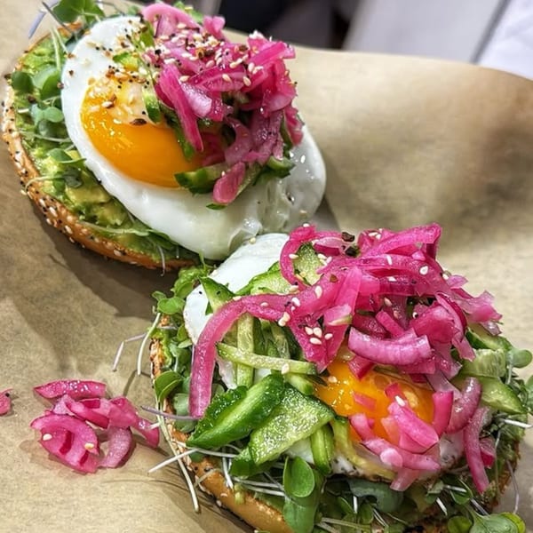 Two Beverly Hills Bagel avocado toasts with fried eggs, pickled onions, and microgreens.