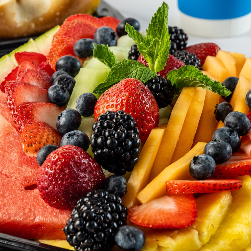 A colorful fruit platter with strawberries, blueberries, blackberries, watermelon, cantaloupe, and mango.