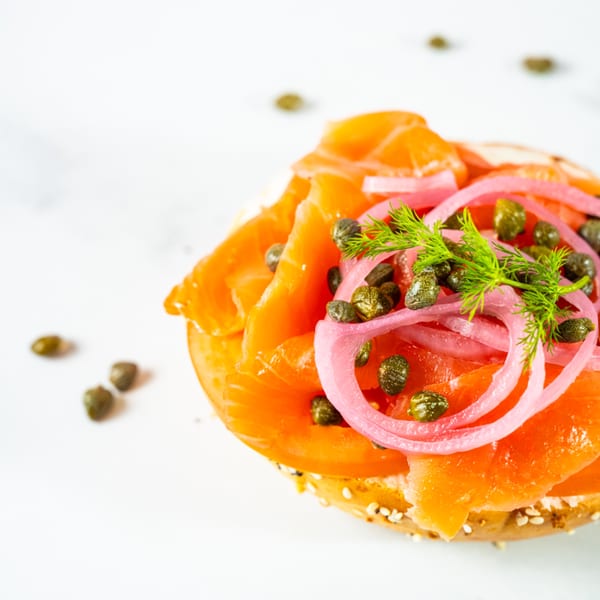 Beverly Hills Bagel's lox bagel with smoked salmon, red onion, capers, and dill on a white background.
